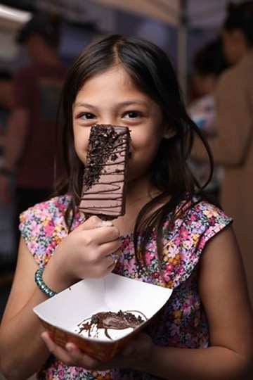 Young guest enjoying a chocolate-dipped paleta with cookie crumbles